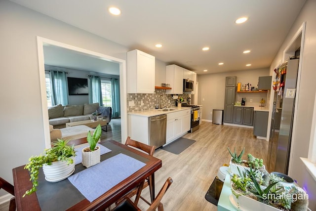 5161 Grand River Dr NE, Grand Rapids, MI 49525 - kitchen featuring stainless steel appliances, light wood-style floors, light countertops, tasteful backsplash, and recessed lighting