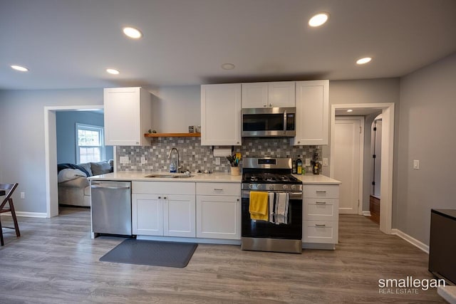 5161 Grand River Dr NE, Grand Rapids, MI 49525 - kitchen featuring appliances with stainless steel finishes, open shelves, white cabinetry, light countertops, and tasteful backsplash