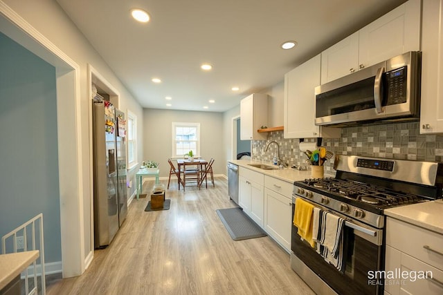 5161 Grand River Dr NE, Grand Rapids, MI 49525 - kitchen featuring appliances with stainless steel finishes, decorative backsplash, light wood-style flooring, white cabinetry, and recessed lighting