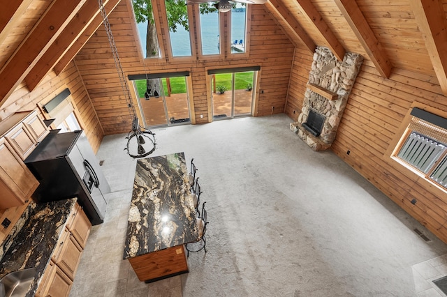 9715 Woodlawn Dr, Portage, MI 49002 - unfurnished living room with wood walls, a stone fireplace, wooden ceiling, carpet flooring, and a water view