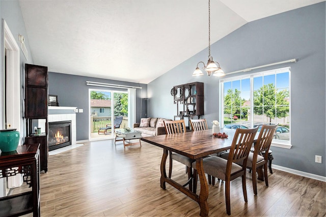 2663 Weatherby Hills Dr SE, Grand Rapids, MI 49546 - dining room featuring vaulted ceiling, wood finished floors, a tile fireplace, and a chandelier