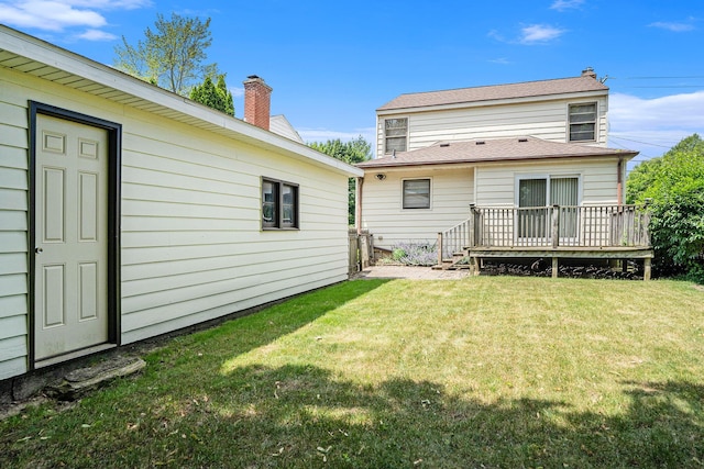 1932 Concord Ave SE, Grand Rapids, MI 49506 - rear view of house with a wooden deck, a lawn, and a chimney
