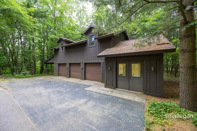 550 Greentree Ln NE, Ada, MI 49301 - view of front of house featuring driveway, an attached garage, and board and batten siding
