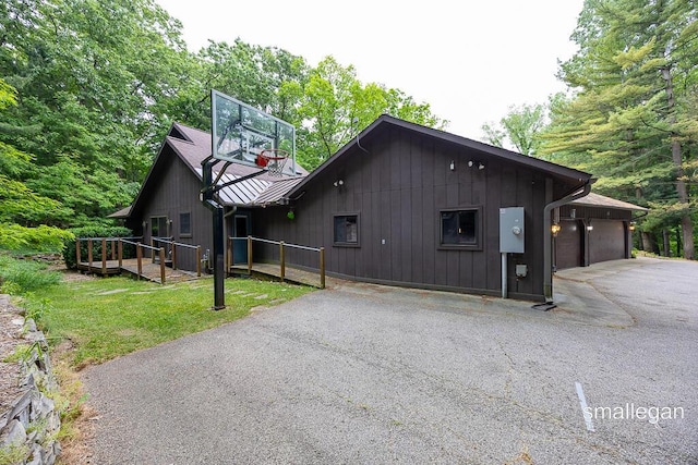 550 Greentree Ln NE, Ada, MI 49301 - view of front of property featuring asphalt driveway, a metal roof, a front lawn, and a deck