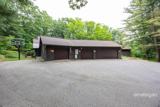 550 Greentree Ln NE, Ada, MI 49301 - garage with asphalt driveway and view of scattered trees