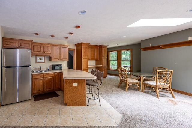 550 Greentree Ln NE, Ada, MI 49301 - kitchen featuring freestanding refrigerator, black microwave, a peninsula, light countertops, and brown cabinets