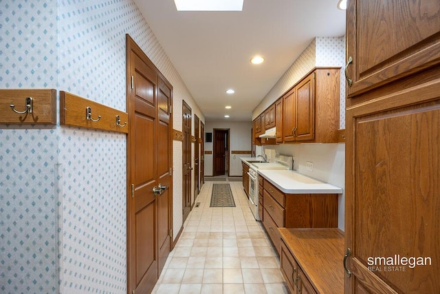 550 Greentree Ln NE, Ada, MI 49301 - kitchen featuring high end stainless steel range, wallpapered walls, brown cabinets, recessed lighting, and light countertops