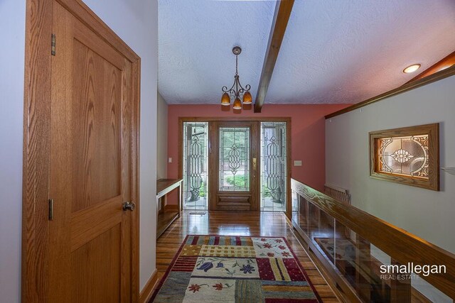 550 Greentree Ln NE, Ada, MI 49301 - entrance foyer featuring a chandelier, a textured ceiling, beam ceiling, and dark wood finished floors