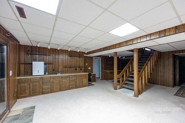 550 Greentree Ln NE, Ada, MI 49301 - finished below grade area featuring a paneled ceiling, wooden walls, stairs, bar with sink, and light colored carpet
