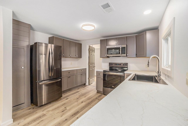1694 S Mill Iron Rd, Muskegon, MI 49442 - kitchen featuring appliances with stainless steel finishes, light wood-type flooring, and light stone countertops