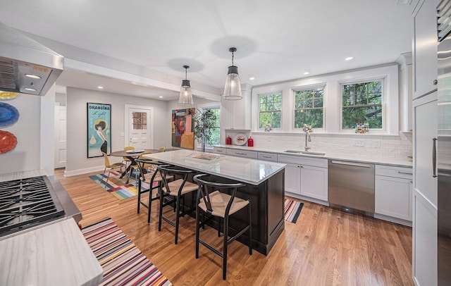 809 Berkshire Rd, Ann Arbor, MI 48104 - kitchen featuring dishwasher, light wood-style flooring, tasteful backsplash, a breakfast bar area, and decorative light fixtures