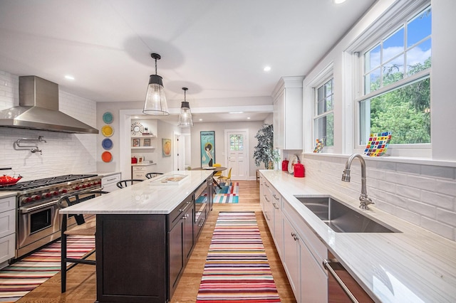 809 Berkshire Rd, Ann Arbor, MI 48104 - kitchen with wall chimney exhaust hood, stainless steel range, decorative backsplash, a breakfast bar, and hanging light fixtures