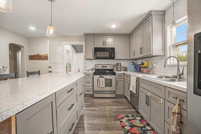 6710 28th Ave, Hudsonville, MI 49426 - kitchen with stainless steel appliances, gray cabinets, dark wood-style flooring, arched walkways, and tasteful backsplash