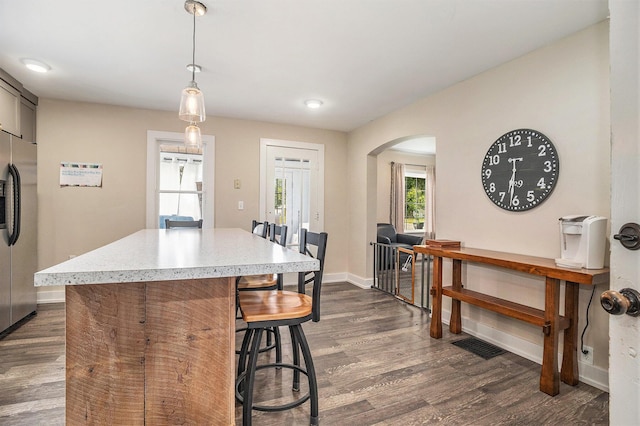 6710 28th Ave, Hudsonville, MI 49426 - kitchen with stainless steel refrigerator with ice dispenser, arched walkways, a breakfast bar area, dark wood-style floors, and light countertops