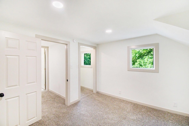 410 Warren Ave, Charlotte, MI 48813 - unfurnished bedroom featuring light carpet, multiple windows, and vaulted ceiling