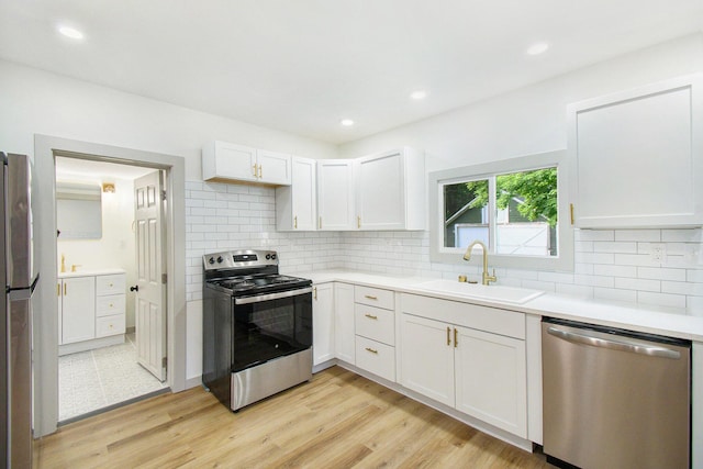 410 Warren Ave, Charlotte, MI 48813 - kitchen with stainless steel appliances, light countertops, backsplash, white cabinetry, and light wood finished floors