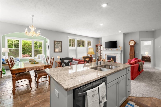 4441 Koinonia Dr NE Unit 3, Grand Rapids, MI 49525 - kitchen with dishwashing machine, a chandelier, a textured ceiling, a kitchen island with sink, and a lit fireplace