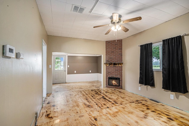 2943 108th Ave, Allegan, MI 49010 - unfurnished living room featuring a ceiling fan, plenty of natural light, a fireplace, and wood finished floors