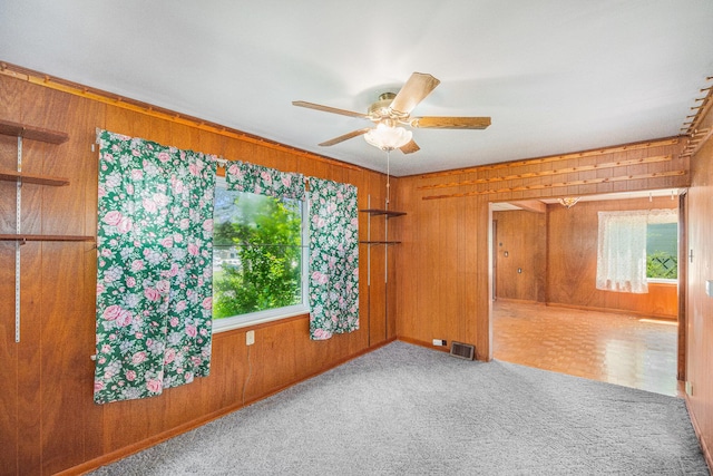 246 Ridgeway Rd, Jackson, MI 49202 - empty room featuring wooden walls, healthy amount of natural light, a ceiling fan, and carpet floors