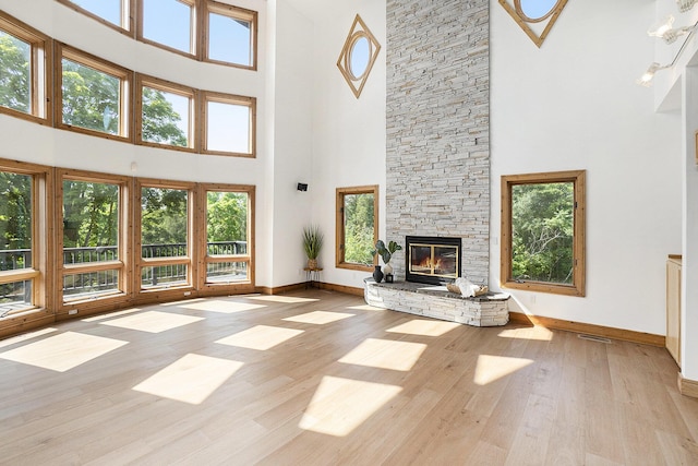 6483 N 144th Ave, Walkerville, MI 49459 - unfurnished living room featuring a towering ceiling, wood finished floors, and a stone fireplace