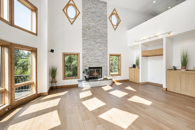 6483 N 144th Ave, Walkerville, MI 49459 - unfurnished living room featuring a high ceiling, a stone fireplace, and light wood-style flooring