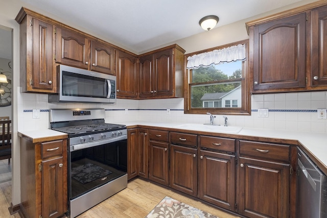 1863 Sunvale Dr SW, Wyoming, MI 49519 - kitchen featuring stainless steel appliances, light wood-type flooring, light countertops, and tasteful backsplash