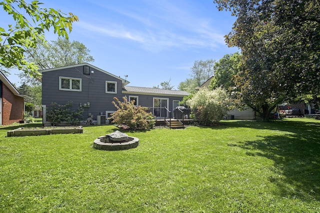 8683 Hemlock Ct, Ypsilanti, MI 48198 - rear view of house with an outdoor fire pit, a wooden deck, and a yard