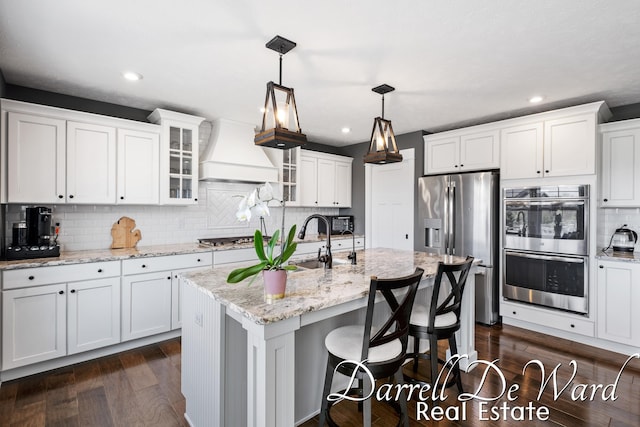 3940 Egypt Valley Ave NE, Ada, MI 49301 - kitchen featuring premium range hood, appliances with stainless steel finishes, backsplash, white cabinets, and dark wood-style floors