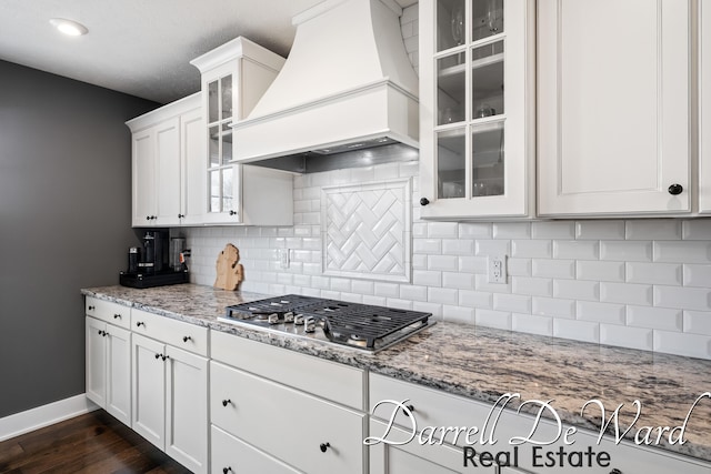 3940 Egypt Valley Ave NE, Ada, MI 49301 - kitchen featuring custom exhaust hood, stainless steel gas stovetop, white cabinetry, dark wood-style flooring, and tasteful backsplash