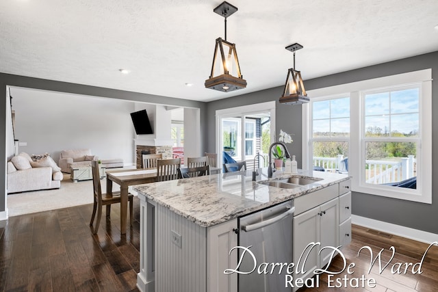 3940 Egypt Valley Ave NE, Ada, MI 49301 - kitchen featuring stainless steel dishwasher, dark wood-style floors, open floor plan, light stone counters, and a kitchen island with sink