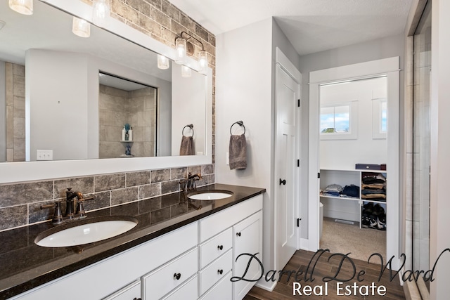 3940 Egypt Valley Ave NE, Ada, MI 49301 - bathroom featuring double vanity, wood finished floors, tasteful backsplash, and a closet