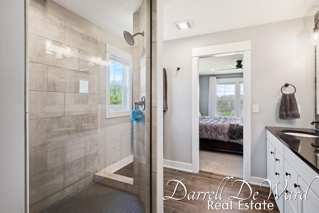 3940 Egypt Valley Ave NE, Ada, MI 49301 - bathroom with double vanity, tiled shower, connected bathroom, a ceiling fan, and wood finished floors