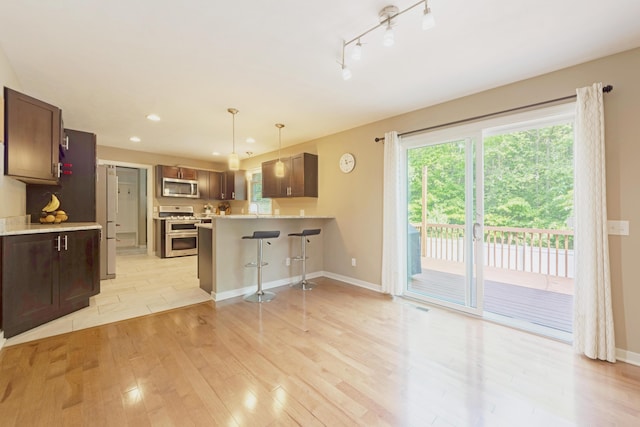 1481 Kristen Path, Saint Joseph, MI 49085 - kitchen with stainless steel appliances, light wood-style flooring, light countertops, a kitchen breakfast bar, and a peninsula