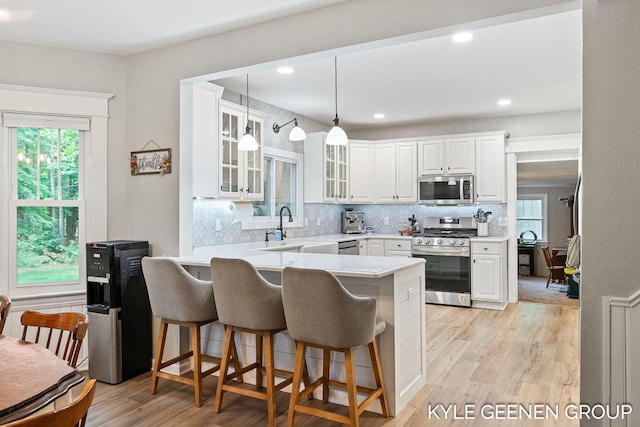 15405 Barry St, West Olive, MI 49460 - kitchen featuring stainless steel appliances, a breakfast bar, a peninsula, glass insert cabinets, and white cabinets