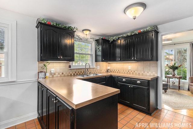 740 Van Raalte Ave, Holland, MI 49423 - kitchen with dark cabinets, light tile patterned floors, a peninsula, and decorative backsplash