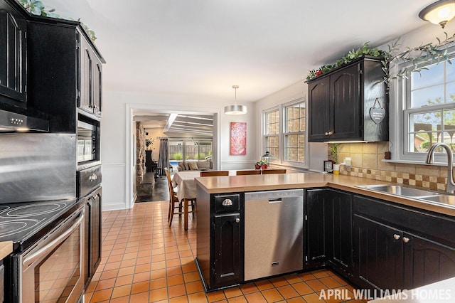 740 Van Raalte Ave, Holland, MI 49423 - kitchen featuring stainless steel appliances, a peninsula, decorative backsplash, light tile patterned flooring, and light countertops