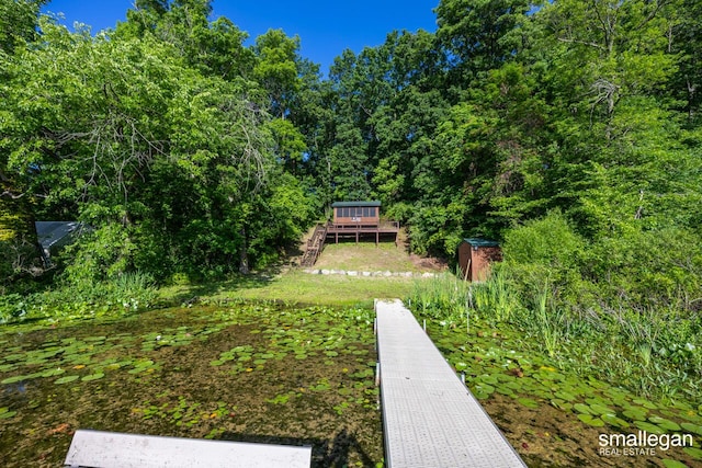 3192 W Sisson Rd, Freeport, MI 49325 - view of yard featuring a storage shed, a deck, stairs, and a forest view