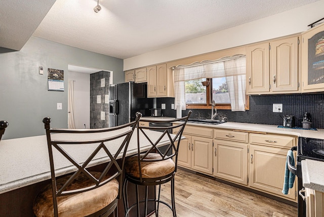 29 Douglas Ave, Coldwater, MI 49036 - kitchen with black refrigerator with ice dispenser, stove, light wood-style floors, tasteful backsplash, and light countertops