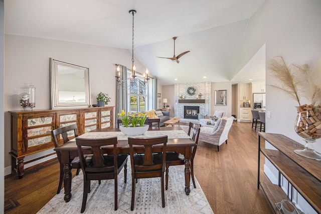3189 Textile Rd, Saline, MI 48176 - dining room with a fireplace, vaulted ceiling, wood finished floors, and a chandelier