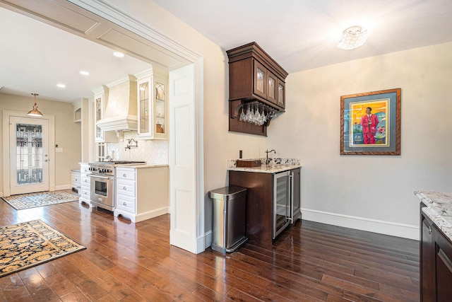 60 Lafayette Ave NE, Grand Rapids, MI 49503 - indoor wet bar featuring high end range, custom exhaust hood, beverage cooler, dark wood-style flooring, and backsplash