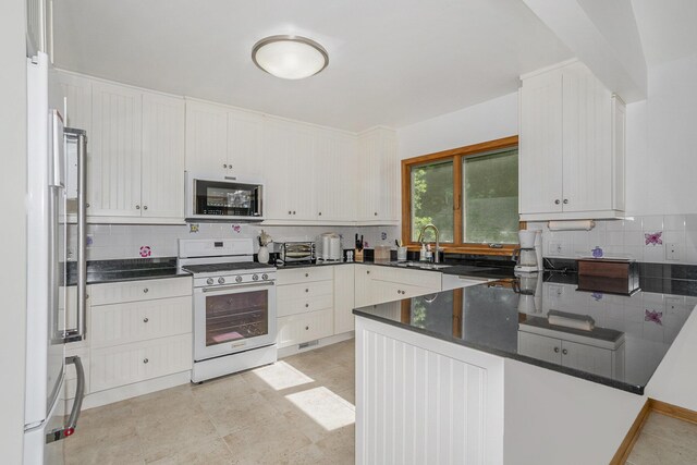 6368 E Lake Ln, Sawyer, MI 49125 - kitchen with white gas range, refrigerator with ice dispenser, decorative backsplash, a peninsula, and dark stone countertops