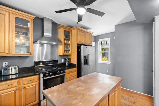 905 Harrison Ave, Saint Joseph, MI 49085 - kitchen featuring wall chimney range hood, stainless steel appliances, light wood-style floors, a kitchen island, and ceiling fan