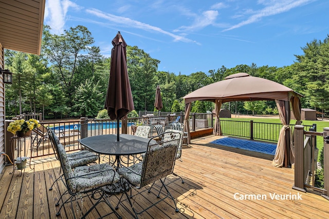 1723 S Sullivan Rd, Ravenna, MI 49451 - wooden terrace with a gazebo, outdoor dining space, and view of wooded area