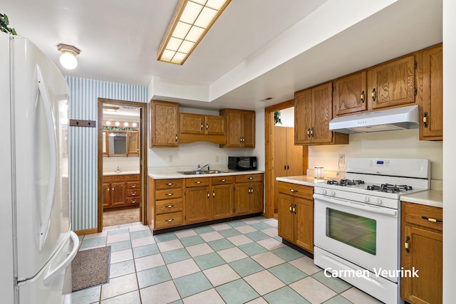 1723 S Sullivan Rd, Ravenna, MI 49451 - kitchen with white appliances, under cabinet range hood, brown cabinets, and light countertops