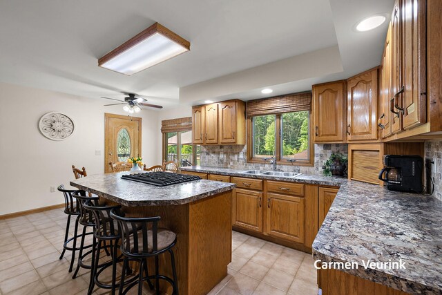1723 S Sullivan Rd, Ravenna, MI 49451 - kitchen featuring a kitchen breakfast bar, stainless steel gas stovetop, decorative backsplash, a kitchen island, and brown cabinets