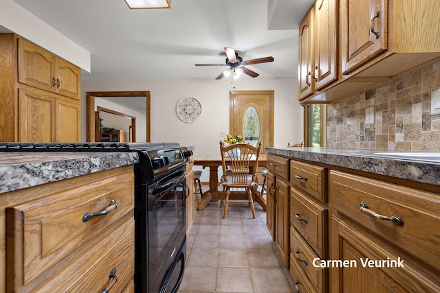 1723 S Sullivan Rd, Ravenna, MI 49451 - kitchen with black range, decorative backsplash, brown cabinetry, a ceiling fan, and light tile patterned floors