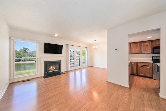 3350 Breckland Ct, Ann Arbor, MI 48108 - unfurnished living room with a chandelier, a fireplace with flush hearth, and light wood-type flooring