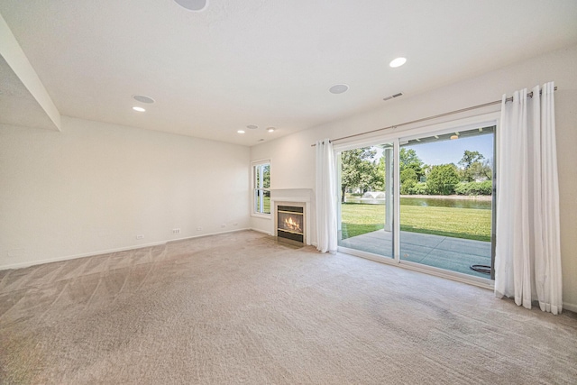3350 Breckland Ct, Ann Arbor, MI 48108 - unfurnished living room featuring light colored carpet, a water view, recessed lighting, and a fireplace with flush hearth