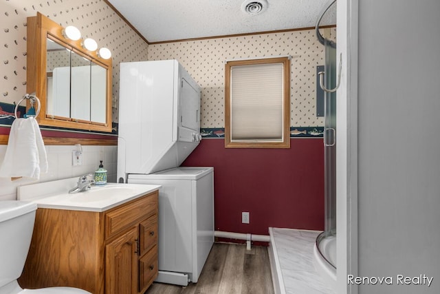 4278 W Joy Rd, Shelbyville, MI 49344 - laundry room with stacked washer / dryer, ornamental molding, wallpapered walls, and wood finished floors
