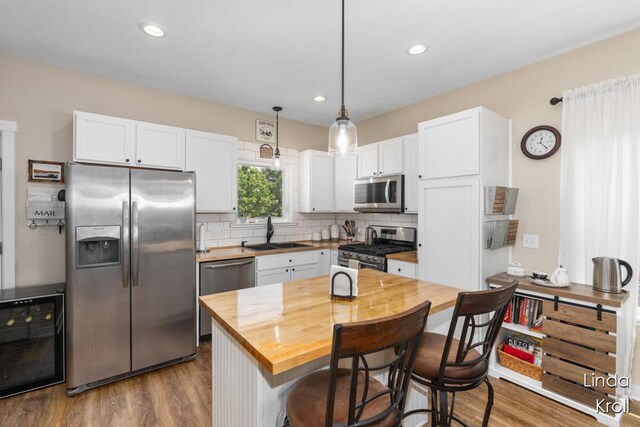 195 Liberty St NW, Sparta, MI 49345 - kitchen featuring stainless steel appliances, wood counters, wine cooler, white cabinets, and tasteful backsplash
